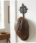 Rock Solid Cast Iron Wall Hook Knockout Vintage Charm For Entryway And Master Bedroom Bullet Proof Heavy Duty Towel And Coat Rack Dead Simple No Sweat Installation In Matte Black Finish With Screws Included Now holding a brown leather cap.