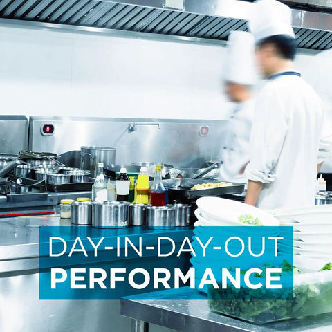 Chefs working in a commercial kitchen with stainless steel hoods, highlighting day-in-day-out performance of exhaust systems