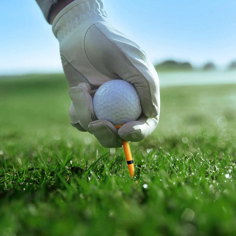 Gloved hand placing a golf ball on a Pro 150 Pack Golf Tees Set With 130 Driver Tees And 20 Iron And Hybrid Tees Durable Reinforced Shaft