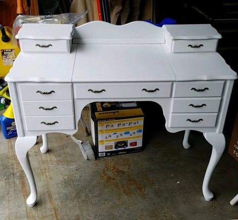 White desk with six drawers featuring antique brass arch style decorative pull handles