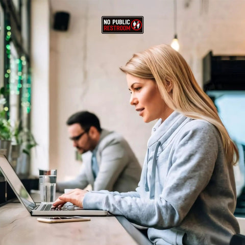 2 Pack No Public Restroom Signs Weatherproof Vinyl Stickers on cafe wall above two people working on laptops