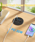 Three Inch Desktop Power Grommet With 35W USB C Fast Charging And Dual 18W USB A Outlets Black Six Foot Cord on a wood desk.