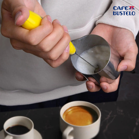Person using Electric Coffee Milk Frother Handheld Battery Operated Drink Mixer With Stainless Steel Whisk And Stand In Bold Yellow