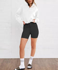 Model wearing Women's Cropped 1/4 Zip Sweatshirt Hoodie With Kangaroo Pocket Lightweight Half Zip Pullover Cozy Relaxed Fit Long Sleeve Top For Fall And Winter Y2K Style White Large with black shorts, standing against a white wall.