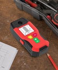 6-in-1 Stud Finder Wall Scanner Magnetic Metal Detector LCD(Red) on a workbench with tools and sketches.