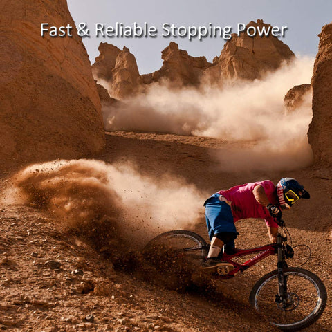 Side view mountain biker in pink shirt on red bike navigating dusty desert trail among rocky formations, helmeted rider.