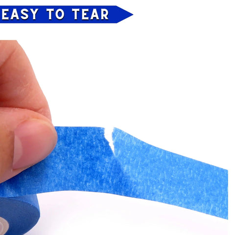 Close-up of hand tearing Blue Painter Tape Set With 1/4 In, 1/2 In, 3/4 In Widths For Pro Grade Precision on white surface