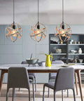 Dining room with three Industrial Spherical Pendant Light With Changeable Cage Design Plug In 15 Ft Cord And On Off Switch Vintage Metal Fixture hanging over a table.