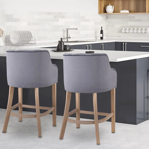 Pair of suede counter height stools with natural wood legs at a kitchen island, 24 inches tall, modern design, extra comfy seats