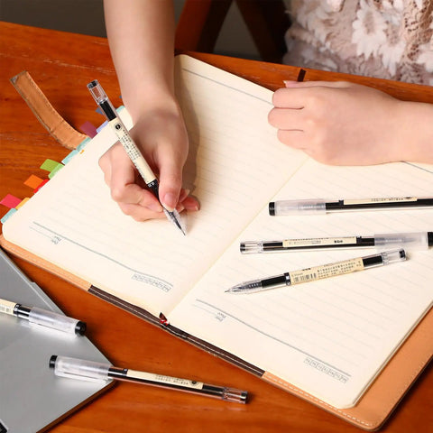 Person writing in a notebook with 12 Pack 0.35mm Black Gel Ink Pens Extra Fine Point for Office and School Use