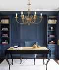 Gold Farmhouse Chandelier With Six Candle Style Lights in office setting, 26-Inch Antique Brass Finish hanging above desk