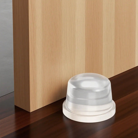 Heavy Duty Clear Silicone Door Stoppers Built Like A Tank With Solid One Inch Base near a wooden wall on a table.