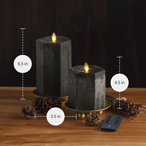Hexagon Flameless Moving Flame Pillar Candles Set Of 2 In Chalky Black Finish Unscented Real Wax 3.5 Inch Width With 4.5 Inch And 6.5 Inch Heights Remote And Timer Included So You Can Cozy Up For Autumn Ambiance, shown on wood table.