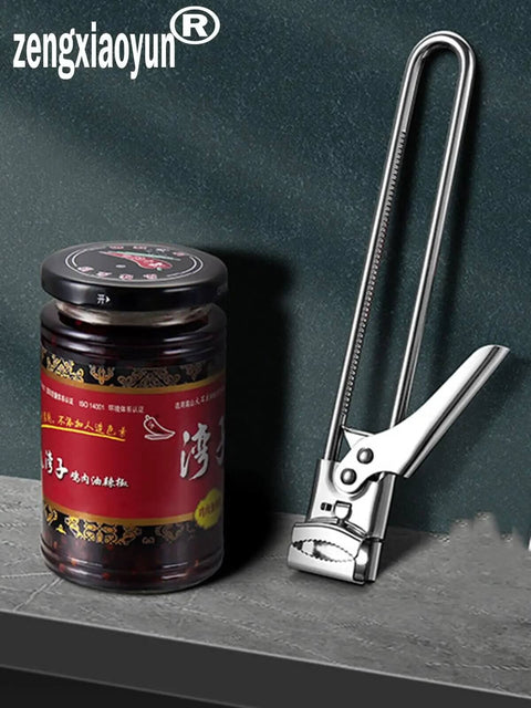 All In One Adjustable Jar And Can Opener No Fuss Stainless Steel Manual Kitchen Gadget With Jar Lid Gripper beside a glass jar