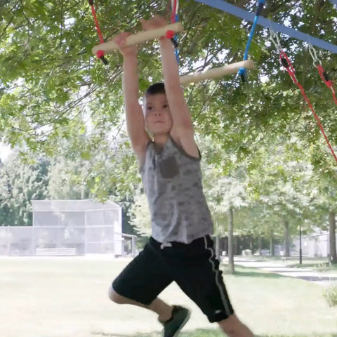 Child swinging on 2 Pack Monkey Bars For Backyard Playset With Ninja Slackline Attachments For Slackline Obstacle Course And Home Playground Equipment Sets Durable Weatherproof Build For Year Round Outdoor Fun Kid Approved