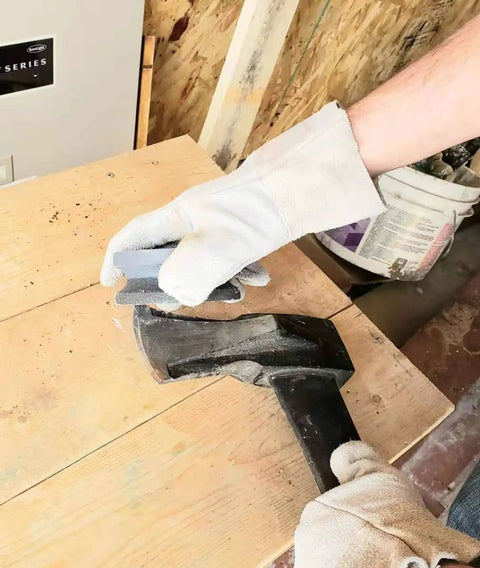 Person using 4 Inch Dual Grit Pro Grade Axe And Hatchet Sharpener Silicon Carbide Stone to sharpen an axe on a wooden table