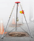 Portable Folding Aluminum Rescue Tripod For Tight Spaces Heavy Duty Fall Arrest Rig With Quick Winch Hookup and Lockdown Anti Drop Guard Gear built for safety near a manhole.