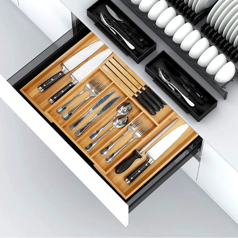 Natural Bamboo Utensil Drawer Organizer Expandable Cutlery Tray With Seven Flexible Slots filled with knives and utensils in a kitchen drawer.