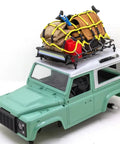 Premium 1/12 Scale Metal Luggage Carrier Roof Rack With Bright Light mounted on an RC truck, holding gear for off-road adventures.