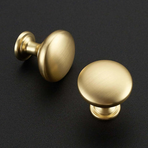Top Shelf Solid Cabinet and Drawer Knob Sets with Kickass Brushed Gold Finish Crafted from Heavy Duty Zinc Alloy for Built Tough Kitchen and Bath Remodel Upgrades. Close-up view of two round brushed gold cabinet knobs.