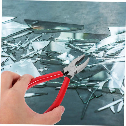 Hand holding Running Pliers For Glass Cutting With Curved Jaw Grozing Tool For Stained Glass Mosaic Fusion Projects over broken glass