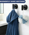 No Sweat Heavy Duty Suction Cup Shower Hooks In Matte Black holding a blue bathrobe and a loofah in a modern bathroom setup.