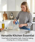 Person in a kitchen pouring milk using a beaker, with ingredients and utensils visible on the countertop.