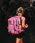 Woman wearing Pink 45L MOLLE Assault Backpack With Bottle Holder And D Rings 3 Day Tactical Rucksack by a waterfall