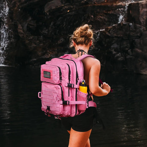 Woman wearing Pink 45L MOLLE Assault Backpack With Bottle Holder And D Rings 3 Day Tactical Rucksack by a waterfall