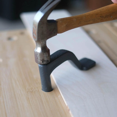 Using a hammer to secure an 8 Inch Bench Holdfast Clamp for Woodworking, Heavy Duty Hold Downs into a workbench for carving or sanding.