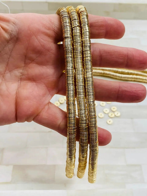 Top Shelf 8mm Gold Disc Brass Spacer Beads Featuring Gleaming 14K Gold Plated Finish held in hand for jewelry making.