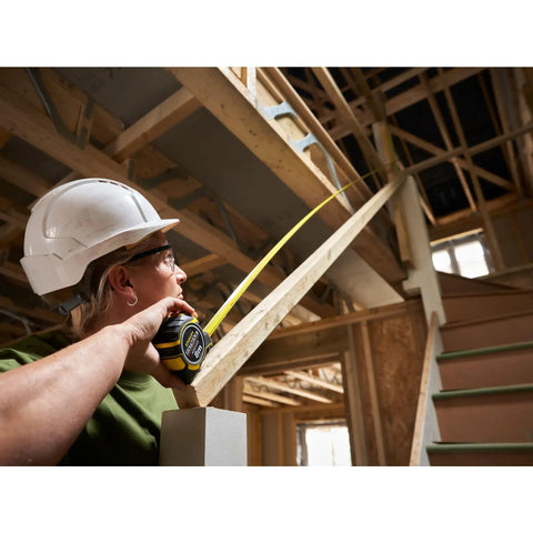 Person using Fatmax Autolock Tape Measure 8m Metric Only Yellow Black, Reverse Lock for one-handed control in construction site