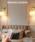Battery Operated Wall Sconces Set Of Two Rechargeable Gold Milk Glass Wireless Lighting shown with remote control in a cozy bedroom.