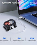 Rechargeable LED Headlamp For Camping And Hiking plugged into laptop via USB cable for charging.