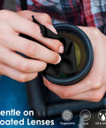 Camera lens cleaning cloth, black microfiber, used to wipe a lens (close-up view)