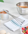 Stainless Steel Ball Whisk With Silicone Tips 10.5 Inch on a napkin near mixing bowls, perfect for sauces and gravies.