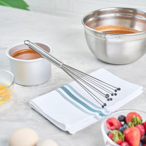 Stainless Steel Ball Whisk With Silicone Tips 10.5 Inch on a napkin near mixing bowls, perfect for sauces and gravies.