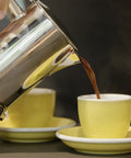 Hella Durable Stainless Steel Stovetop Espresso Maker pouring rich coffee into a yellow cup on a saucer.