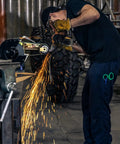 Hella Versatile 2 X 36 Belt Grinder Attachment For Bench Tools in action, sparks flying from grinding metal in workshop.