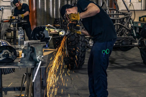 Hella Versatile 2 X 36 Belt Grinder Attachment For Bench Tools in action, sparks flying from grinding metal in workshop.