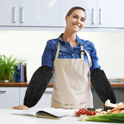 Tough As Nails Four Pack Waterproof Arm Sleeves With Thick Elbow Guards Grease Proof Oil Resistant Protective Oversleeves For Mechanics Shop Floor And Weekend Grind In Black worn by a woman in the kitchen.