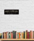 Acrylic 9x3 Inch Free Library Sign Self Stick Door Wall Signage in royal black finish above a row of books on a shelf.