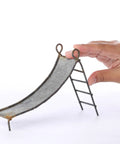 Miniature Rustic Metal Slide For Fairy Garden Bench And Backyard Micro Landscape Set featuring a hand for size reference.