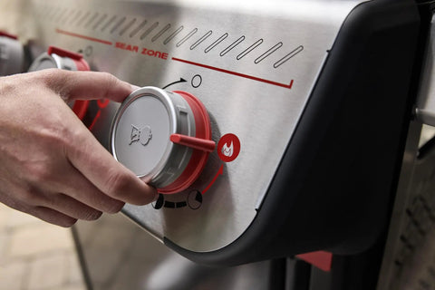 Hand adjusting dials on E-325 Propane Gas Grill With 3 Burners And 2 Boost Burners, Bold Sear Zone Heat, Stainless Controls