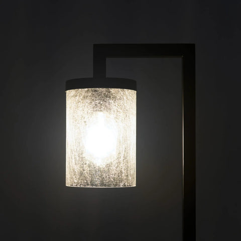 Illuminated modern lamp with frosted cylindrical shade against dark background