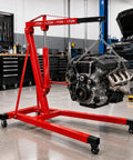 Heavy Duty 5000 Lbs Folding Engine Hoist With 8 Ton Hydraulic Pump Cherry Picker Crane lifting an engine in a garage setting.