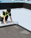 A worker applying No Nonsense Heavy Duty Waterproof Aluminum Foil Tape For Roof And Camper Leaks Thick Self Adhesive Polymer Asphalt Roll That Beats Bad Weather Easy Peel And Stick Patch Measuring Three Point Three By Twenty Six Feet Wide And Strong on a roof.