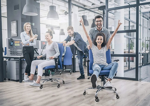 Group of people having fun in an office, using desk chairs with heavy duty rubber chair casters 3 inch replacement wheels.