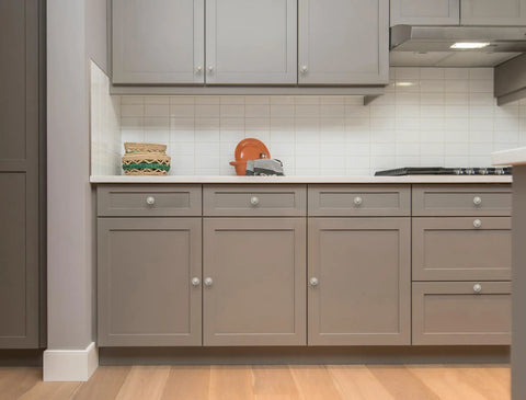 Sleek Brushed Nickel Round Knobs on gray kitchen cabinets, highlighting modern design with storage and decor accents.