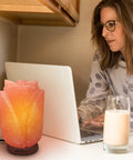 Flower Shape Pink Himalayan Salt Lamp With Wood Base And Dimmer beside laptop on desk, glowing with cozy vibes